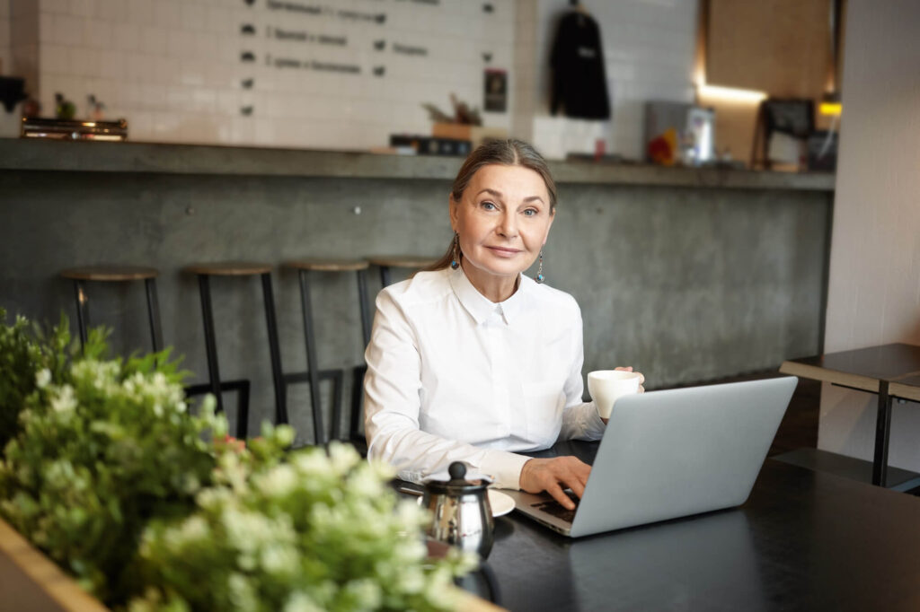 people-leisure-modern-technologies-concept-picture-blue-eyed-elderly-lady-sitting-cafe-table-front-open-laptop-computer-using-wireless-internet-connection-drinking-coffee (1)